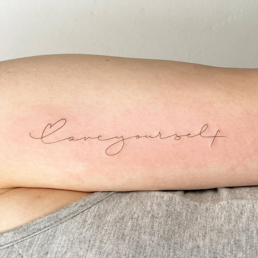 Love yourself" lettering tattoo located on the bicep.